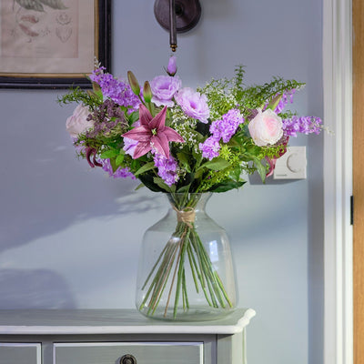 Bouquet of flowers in a vase on a table next to a wooden door.