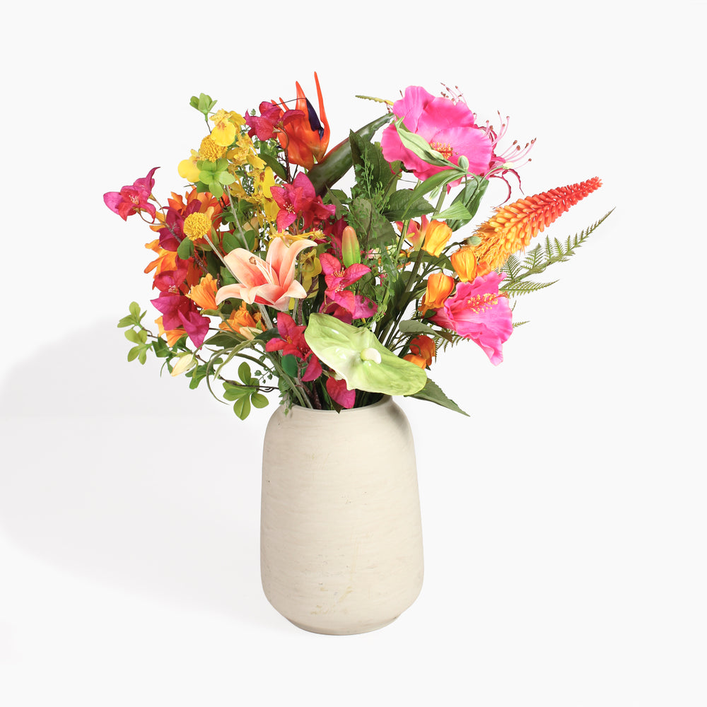 A vibrant artificial flower arrangement in a textured cream-colored ceramic vase, set against a clean white background.