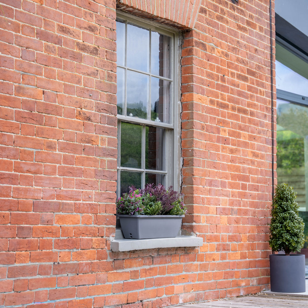 Brick building exterior with window box plants and wooden deck