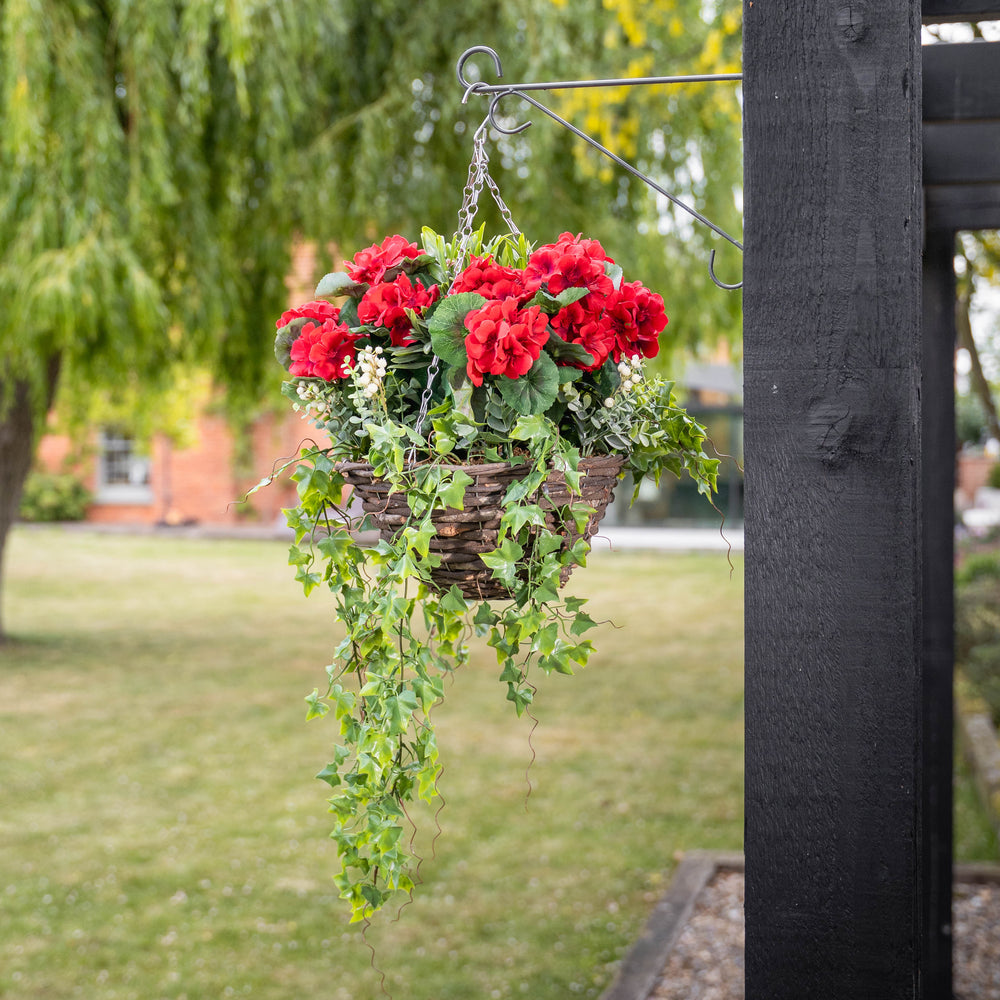 Red flowers and foliage in a basket, hanging on a bracket in a garden