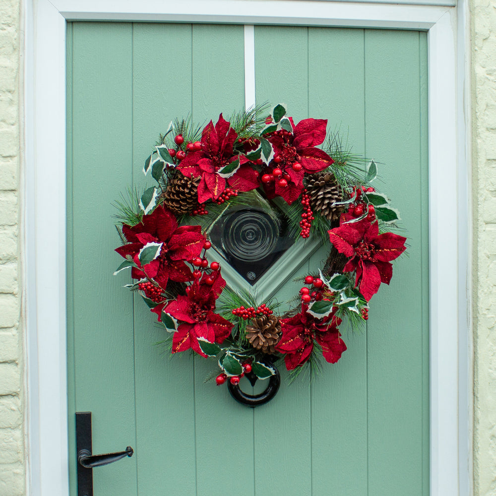 Red floral wreath with pinecones on a green door