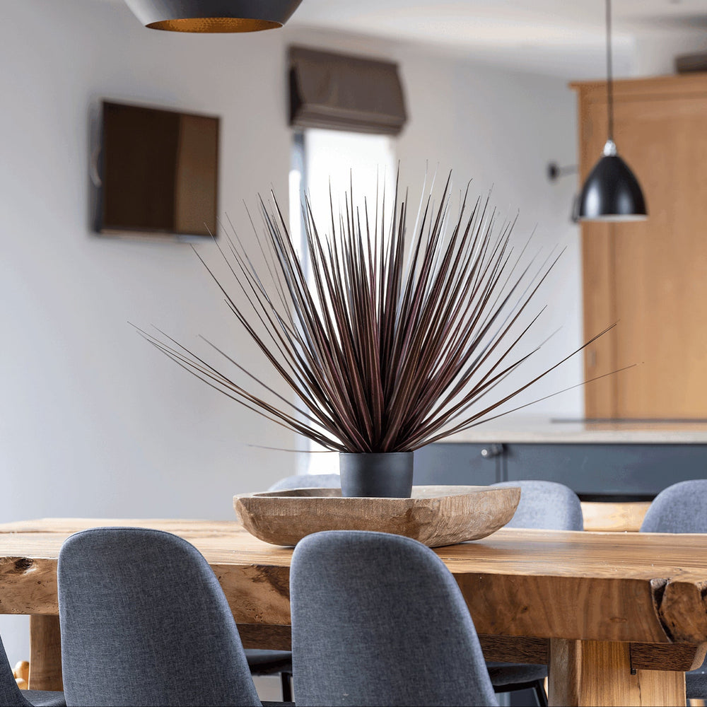 Dining area with wooden table, gray chairs, and decorative plant in a modern kitchen setting.