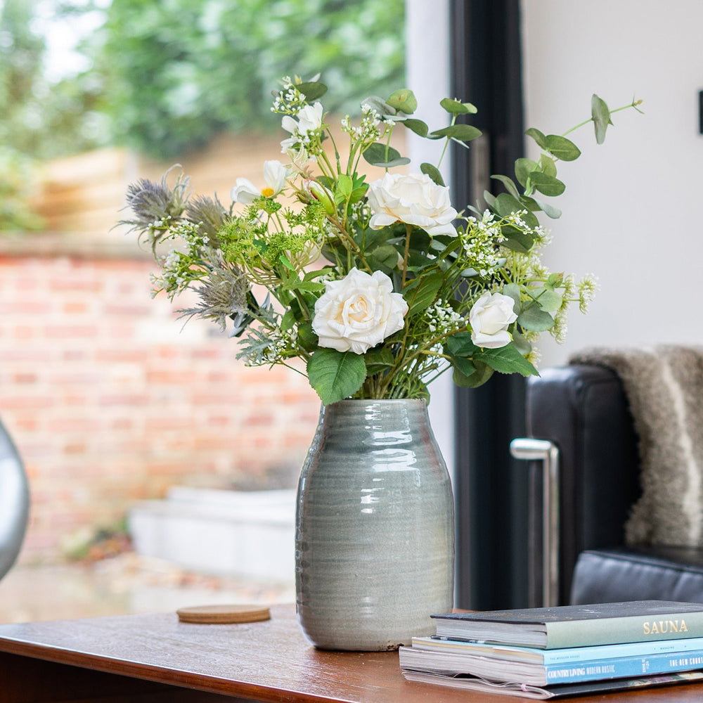 Vase with flowers on a wooden table in a living room