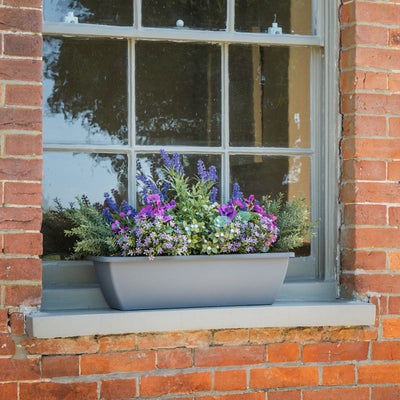 Window box with flowers on a brick window sill