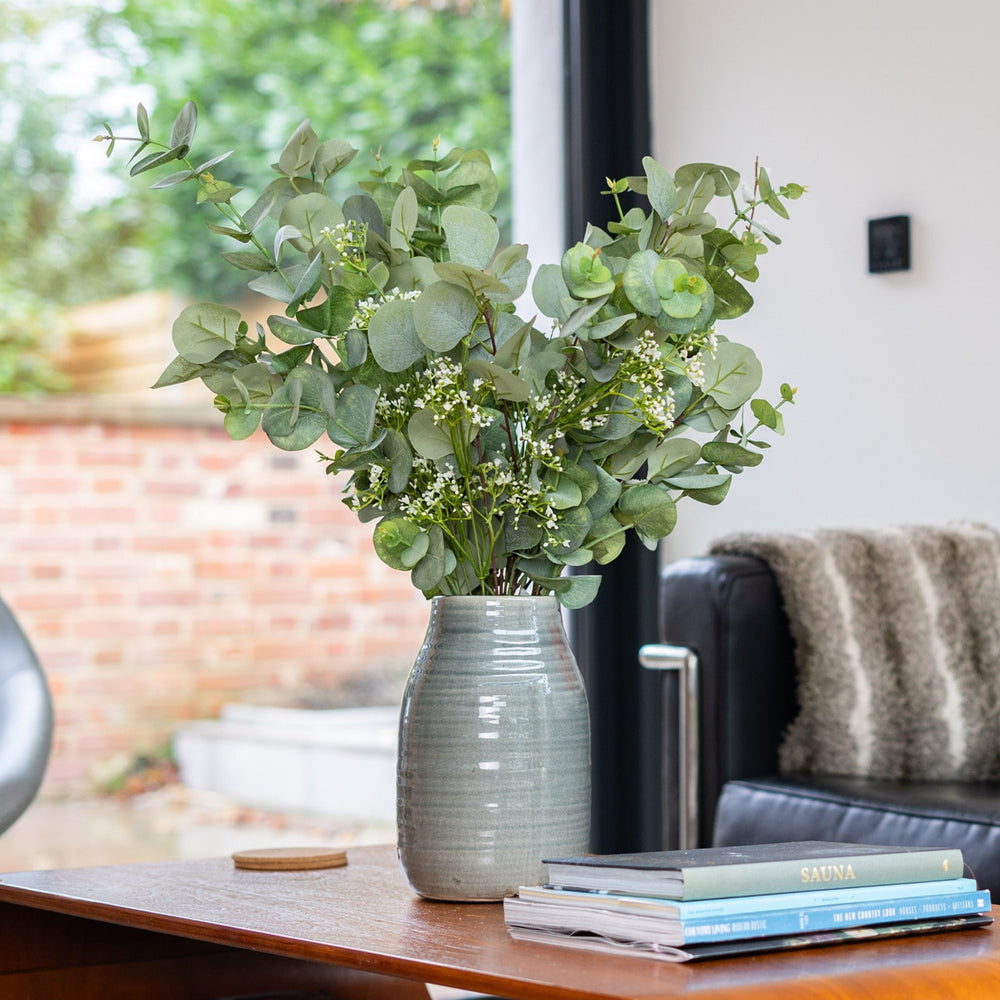 Green vase with eucalyptus on a table in a living room