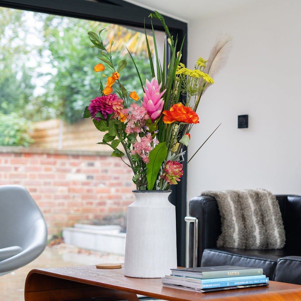 Colorful flowers in a vase on a wooden table in a living room.