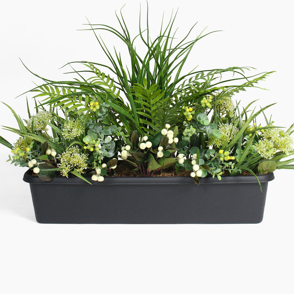 Artificial greenery arrangement in a black container on a white background