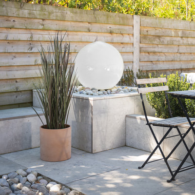Outdoor patio with a water feature, potted plant, and chairs.
