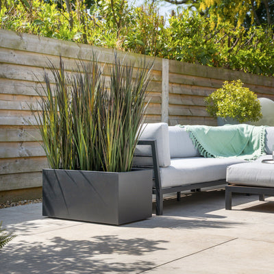 Outdoor patio with a sofa, planters, and wooden fence
