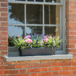 Window box with flowers on a brick window sill