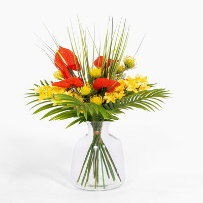 Bouquet of red and yellow flowers in a clear vase on a white background