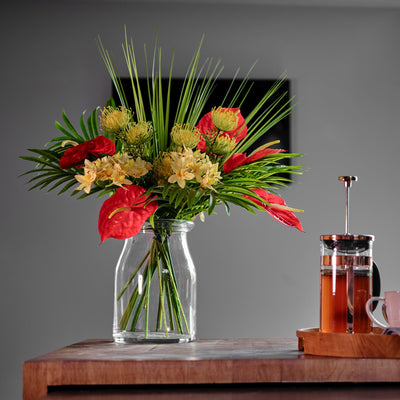 Bouquet of flowers in a clear vase on a wooden table with a blurred background