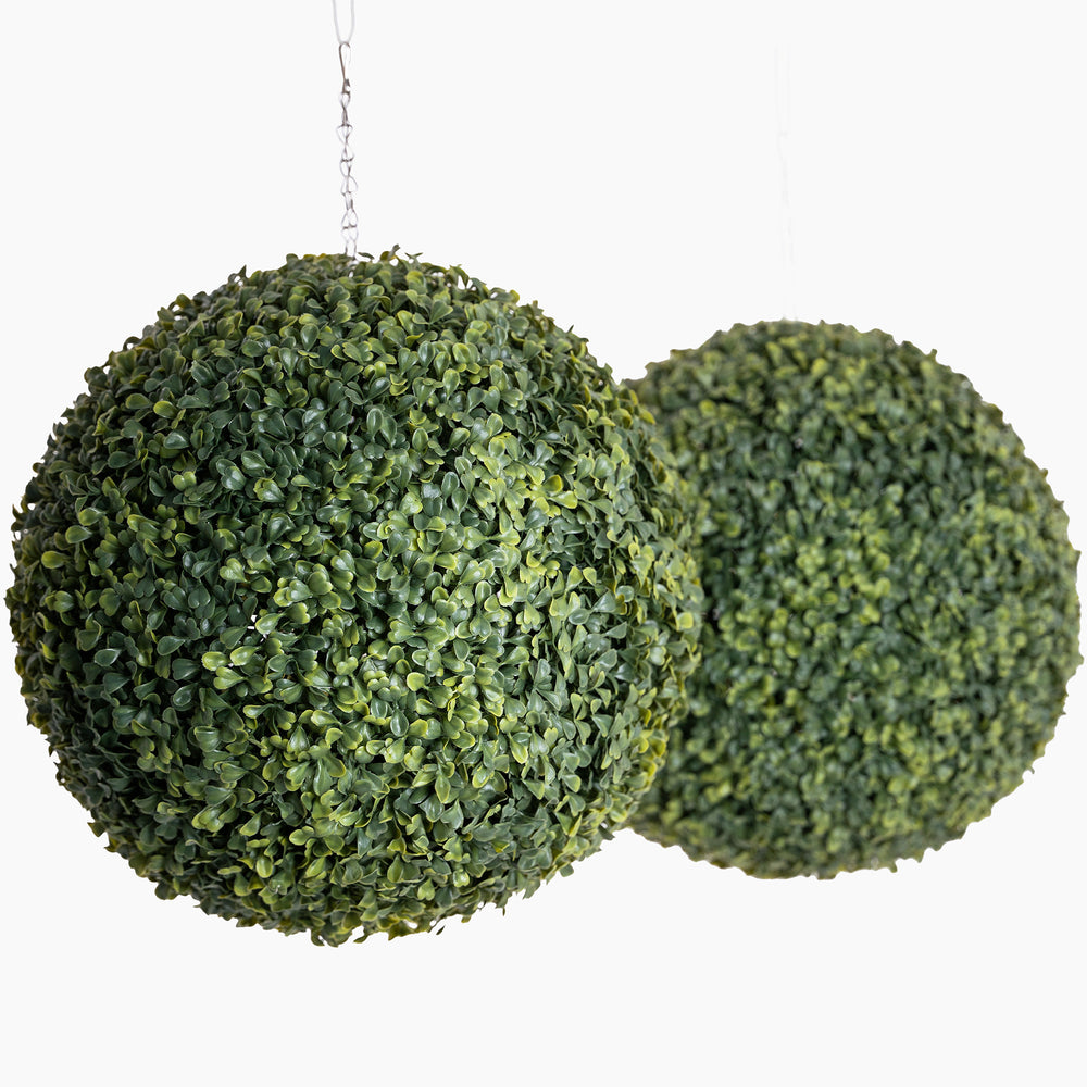 Two artificial green spherical plants on a white background