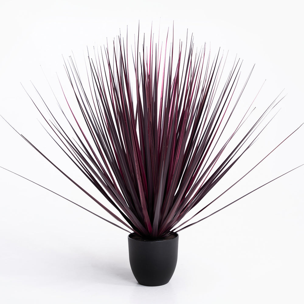 Artificial plant with long, thin leaves in a black pot on a white background