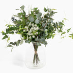 Bouquet of greenery in a clear vase on a white background