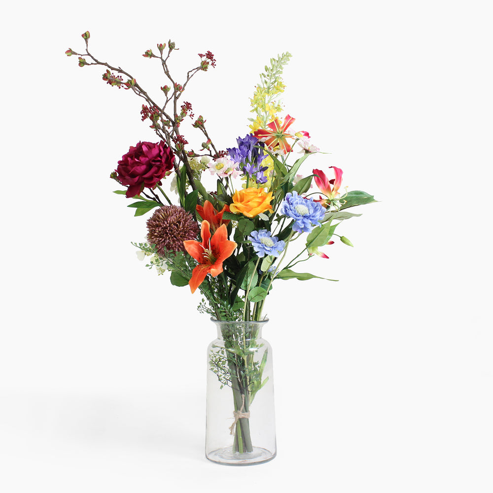 Bouquet of colorful flowers in a clear glass vase on a white background