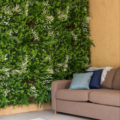 Living wall with greenery next to a brown sofa in a room with a glass door.
