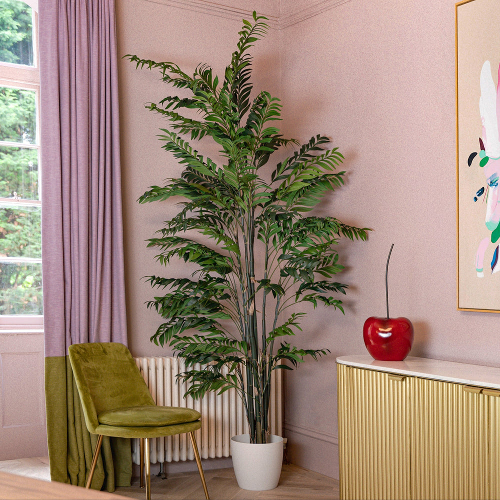 Room interior with a green chair, tall plant, and colorful abstract painting on a pink wall.