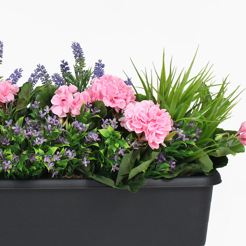 Floral arrangement with pink flowers and greenery in a black pot on a white background