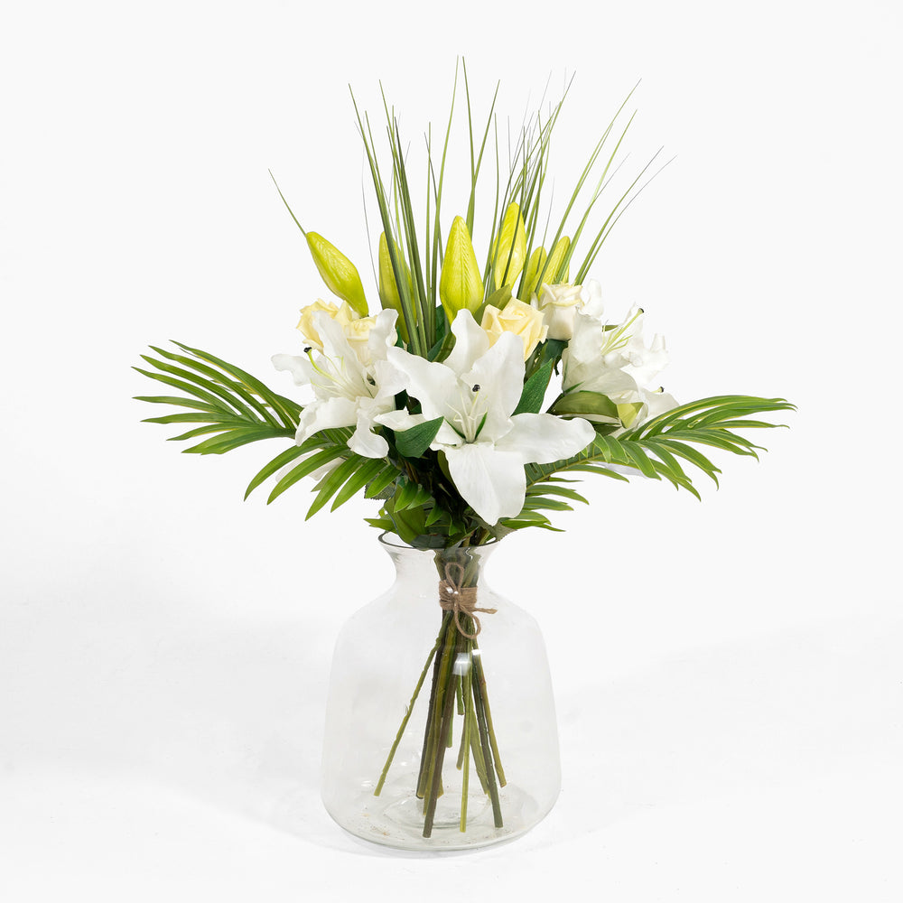 Bouquet of white and yellow flowers in a clear glass vase on a white background
