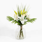 Bouquet of white and yellow flowers in a clear glass vase on a white background