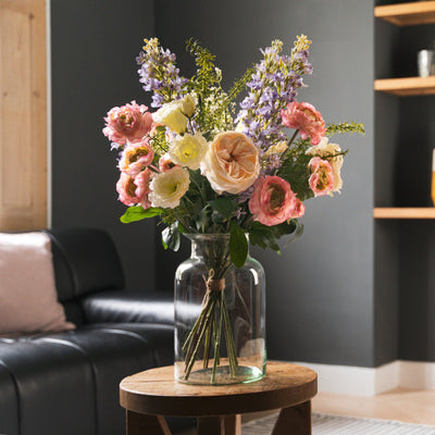 Bouquet of flowers in a vase on a wooden table in a living room.