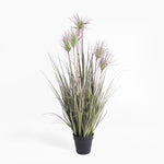 Potted artificial plant with long green leaves and pinkish-purple flowers on a white background