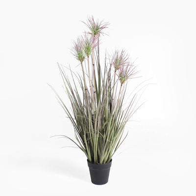 Potted artificial plant with long green leaves and pinkish-purple flowers on a white background