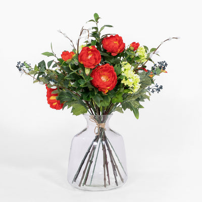 Bouquet of red and green flowers in a clear vase on a white background