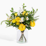 Bouquet of yellow and white flowers in a clear vase on a white background