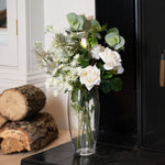 Vase with flowers on a fireplace hearth next to stacked logs