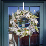 Decorative wreath with greenery and ornaments hanging on a door.