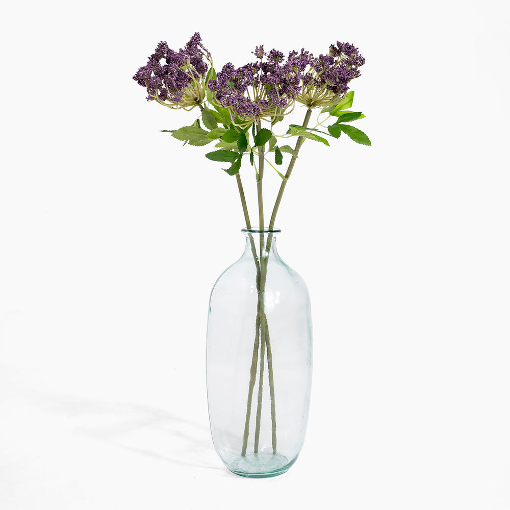 Clear glass vase with purple flowers on a white background