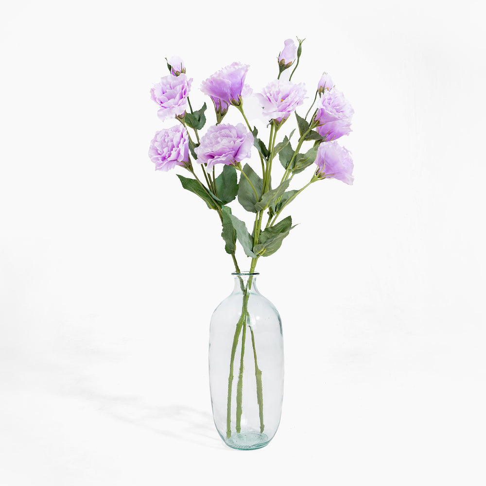 Clear glass vase with purple flowers on a white background