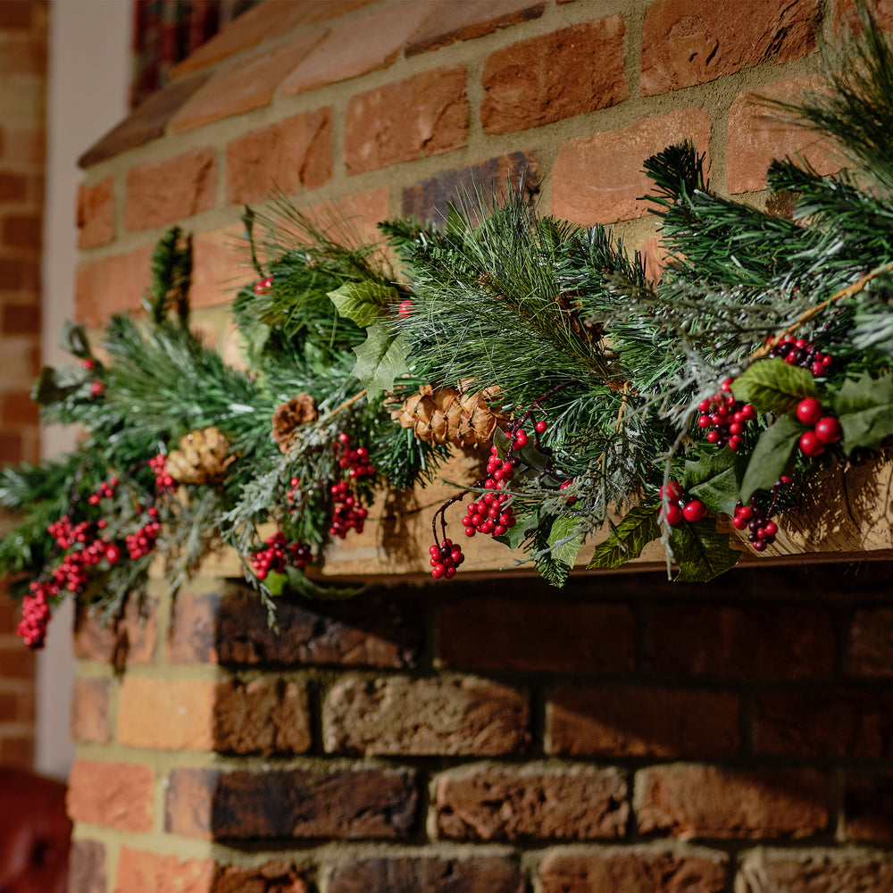 Decorative Christmas garland with greenery and berries on a brick fireplace.