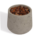 A small cylindrical concrete planter with a textured light gray finish, filled with chunky brown bark chips, shown on a white background.