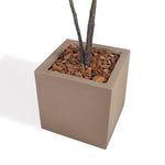 A square concrete planter in a warm taupe-brown color, filled with brown wood chips and dark tree trunks planted, shown on a clean white background.