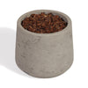 A small cylindrical concrete planter pot filled with brown wood chips or bark, photographed on a clean white background.