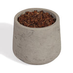 A small cylindrical concrete planter pot filled with brown wood chips or bark, photographed on a clean white background.