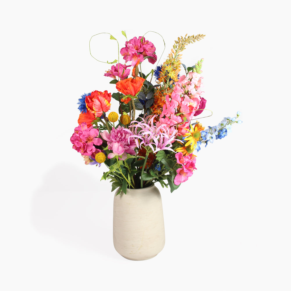 A vibrant artificial flower arrangement in a textured beige ceramic vase, set against a plain white background.