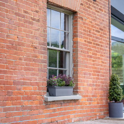 Brick building exterior with window box plants and wooden deck