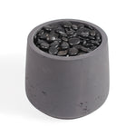 A dark gray concrete planter pot filled with smooth black decorative stones, shown on a clean white background.