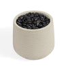A cylindrical fibreclay pot filled with smooth black decorative stones, shown on a clean white background.
