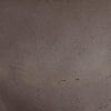 A close-up texture shot of a dark brown, matte, and slightly granular material surface.