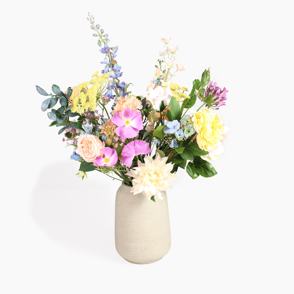 A vibrant artificial flower bouquet in a textured beige ceramic vase, set against a clean white background.