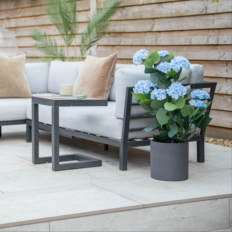 Outdoor patio setting with a sofa, coffee table, and potted plants.