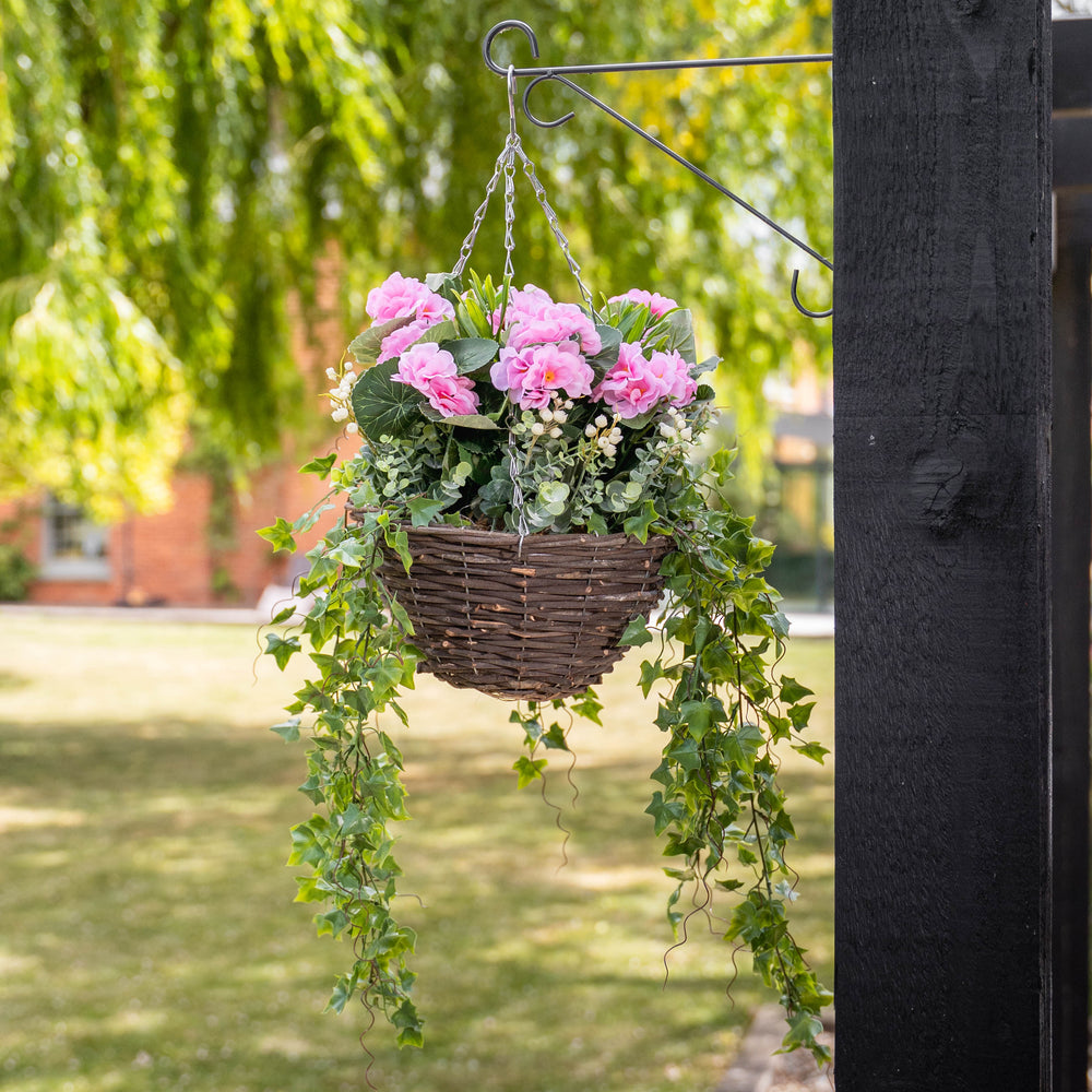 Pink flowers and foliage in a basket, hanging on a bracket in a garden
