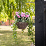 Pink flowers and foliage in a basket, hanging on a bracket in a garden