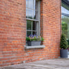 Brick building with a window box and potted plants on a wooden deck