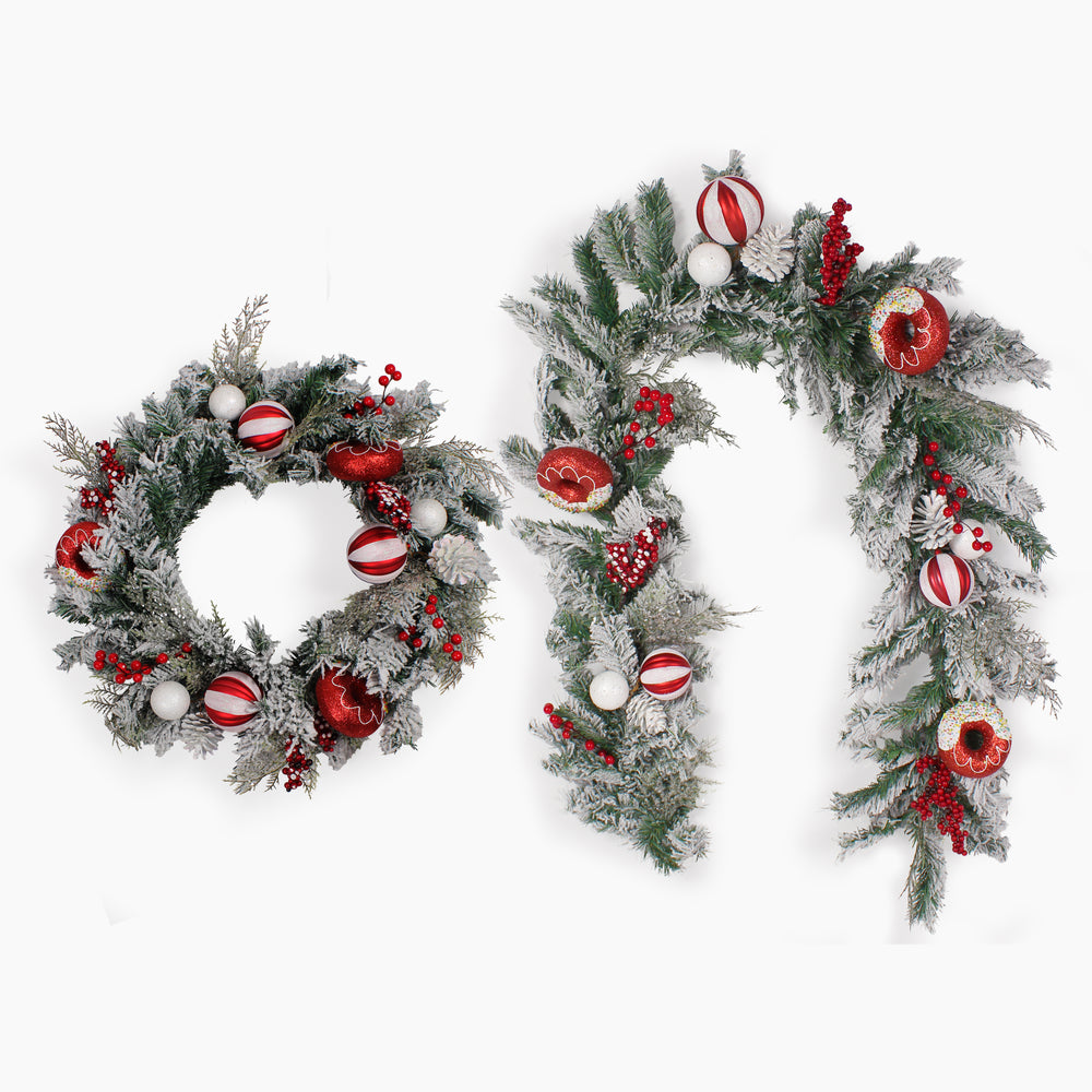 A festive holiday garland set featuring a circular wreath and a garland, both decorated with faux snow, green pine branches, red berries, red and white striped ornaments, and frosted doughnuts, shown against a plain white background.